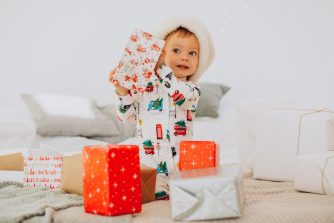 Kisfiú karácsonyi pizsamában ajándékokat bont